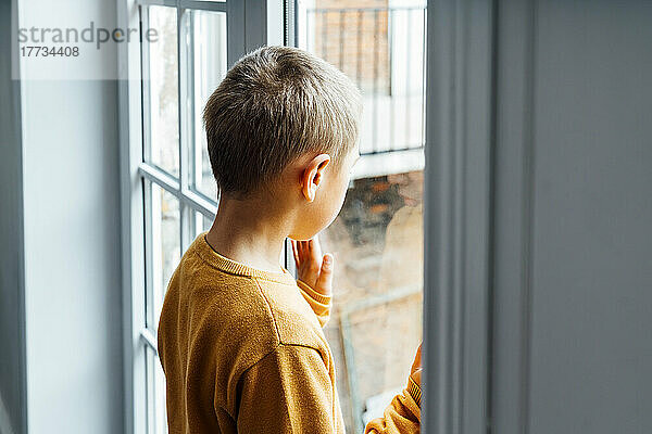 Junge schaut zu Hause durch das Fenster