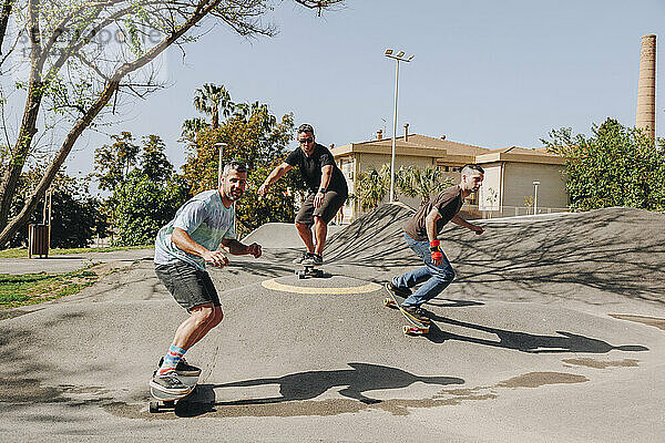 Männer fahren an einem sonnigen Tag auf der Sportrampe Skateboard