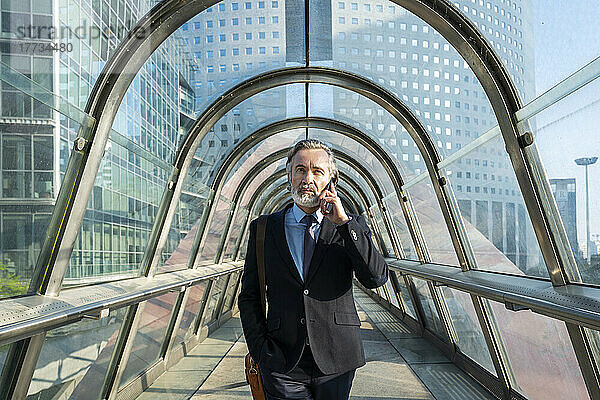 Reifer Geschäftsmann spricht über Smartphone auf Fußgängerbrücke