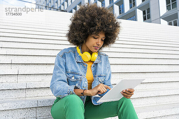 Afro-Frau benutzt Tablet-PC und sitzt auf Stufen