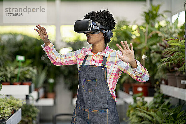 Gärtner mit Virtual-Reality-Headset gestikuliert in der Gärtnerei