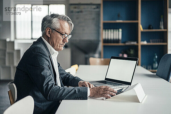 Geschäftsmann nutzt Tablet-PC und Laptop auf dem Schreibtisch im Büro
