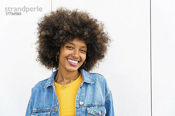 Glückliche schöne Frau mit Afro-Frisur vor der Wand