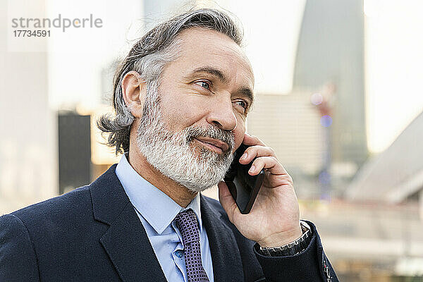 Reifer Geschäftsmann  der am Smartphone spricht