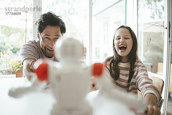 Glücklicher Vater und Tochter spielen zu Hause mit Spielzeugroboter