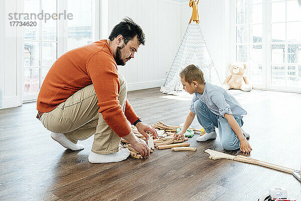 Vater und Sohn bauen zu Hause Spielzeugeisenbahnschienen