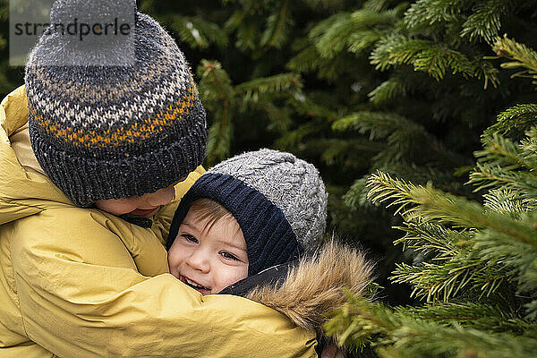 Brothers embracing by Christmas tree