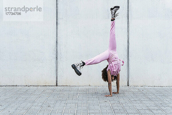 Carefree girl practicing handstand in front of wall