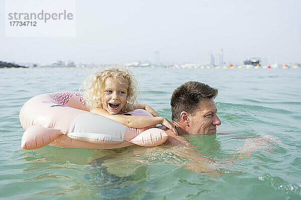Glückliches Mädchen mit Vater  der im Meer schwimmt