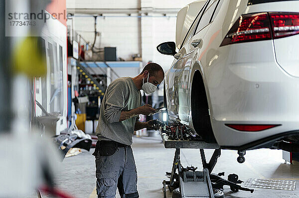 Mechaniker fotografiert Autoteil in Garage