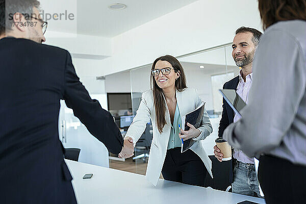 Geschäftsfrau schüttelt einem Kollegen im Büro die Hand