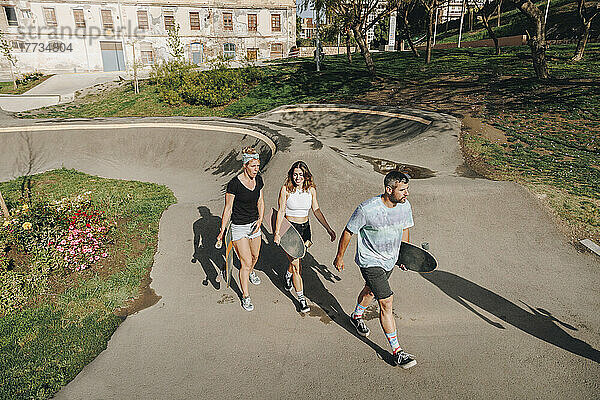 Männer und Frauen halten Skateboards und laufen auf der Sportrampe