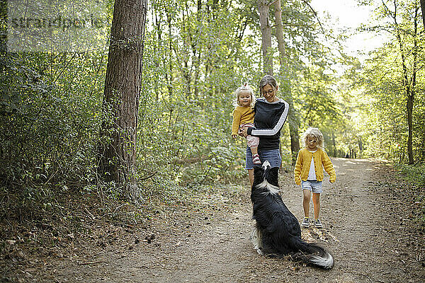 Frau mit Töchtern und Hund im Wald