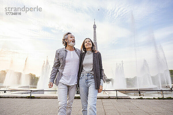 Fröhlicher reifer Mann und Frau gehen vor Brunnen und Eiffelturm  Paris  Frankreich