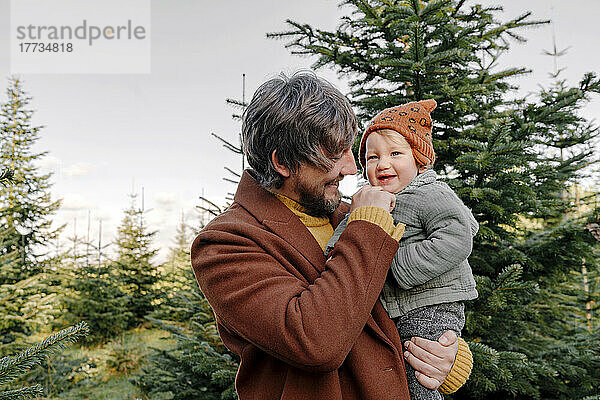 Vater genießt mit süßem Sohn auf der Weihnachtsbaumfarm