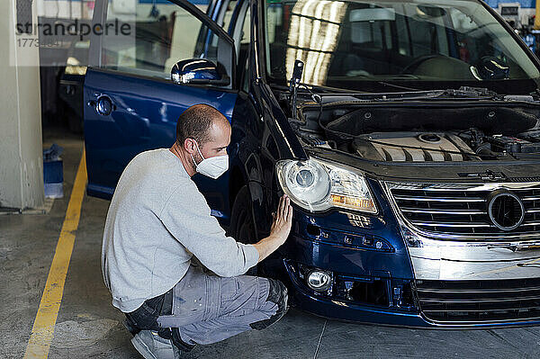 Automechaniker analysiert Autostoßstange in Werkstatt