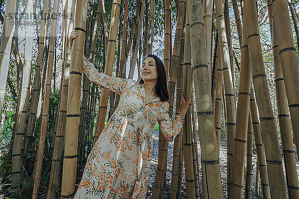 Woman with eyes closed standing in bamboo grove