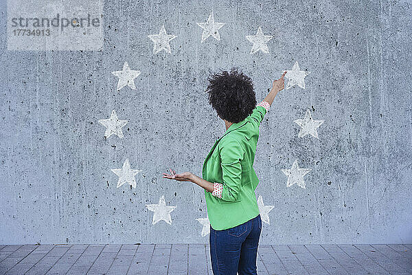 Frau zeigt auf an die Wand gemalte europäische Sterne