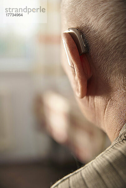 Älterer Mann trägt zu Hause Hörgerät