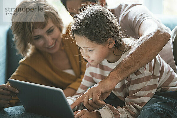 Eltern mit Tochter nutzen Tablet-PC zu Hause