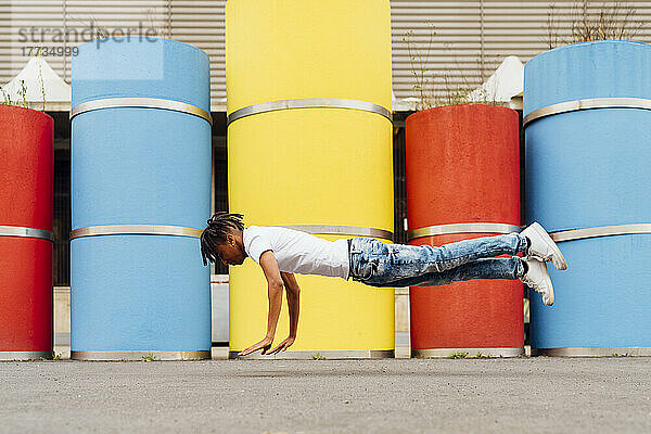 Junger Mann in Plankenposition springt vor Betonrohren