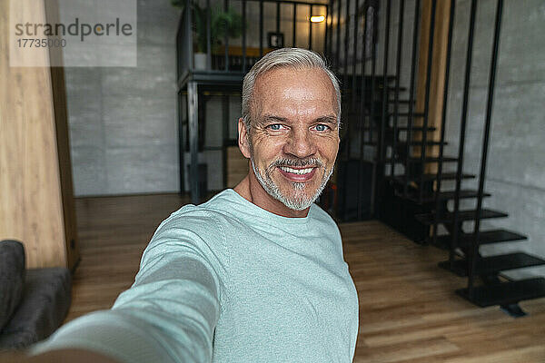 Smiling man taking selfie at home