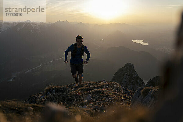 Mann rennt bei Sonnenuntergang auf den Sauling-Berg