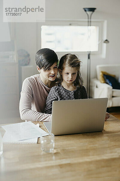 Mutter und Tochter schauen gemeinsam am Schreibtisch auf den Laptop