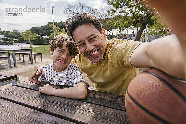 Fröhlicher Mann mit Sohn  der an einem sonnigen Tag ein Selfie macht