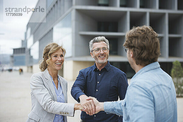 Happy businessmen and businesswoman shaking hands