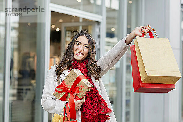 Glückliche junge Frau hält Einkaufstüten mit Weihnachtsgeschenk