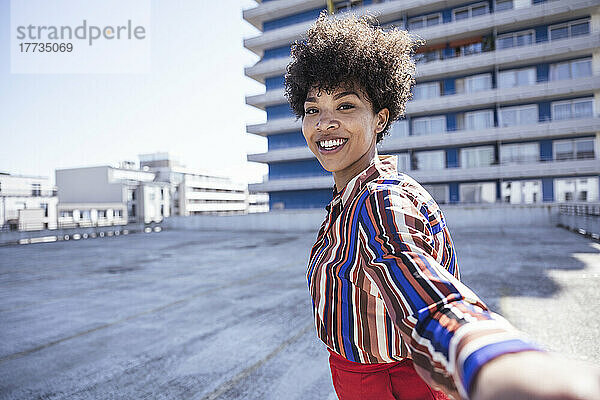 Glückliche Frau mit Afro-Frisur  die Spaß auf dem Parkdeck hat