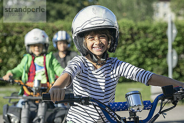 Lächelnder Junge mit Sporthelm  der beim Verkehrserziehungstraining Quad fährt