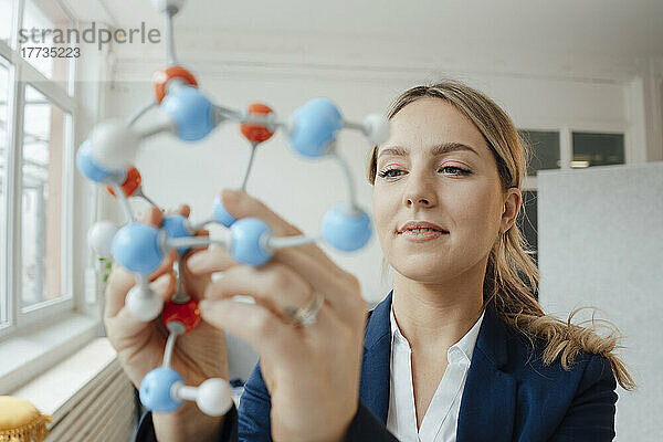 Schöne Geschäftsfrau analysiert molekulares Modell im Büro