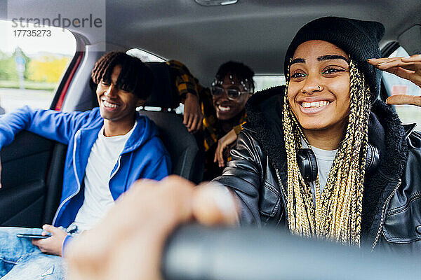 Lächelnde Frau sitzt mit Freunden im Auto