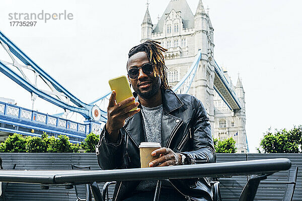 Mann mit Sonnenbrille SMS auf Smartphone  London  England