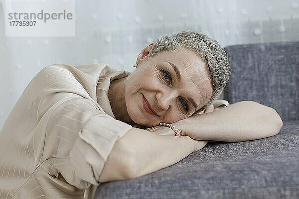 Porträt einer reifen Frau mit kurzen grauen Haaren  die auf der Couch lehnt