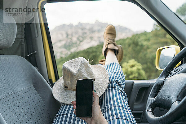 Hand einer Frau mit Mobiltelefon im Lieferwagen