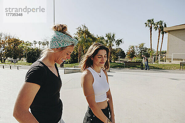 Fröhliche Freunde unterhalten sich an einem sonnigen Tag im Skateboardpark