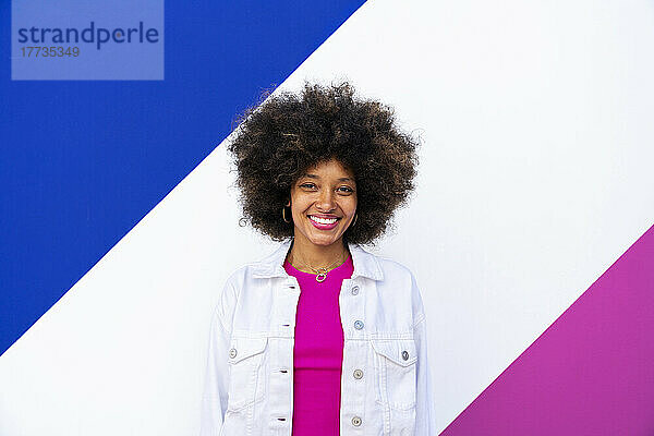Glückliche junge Afro-Frau vor einer bunten Wand