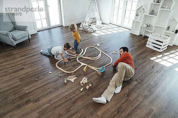 Vater liegt auf dem Boden  Sohn spielt zu Hause mit Spielzeugeisenbahn