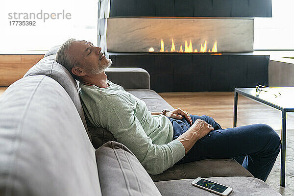 Man with eyes closed resting on sofa at home