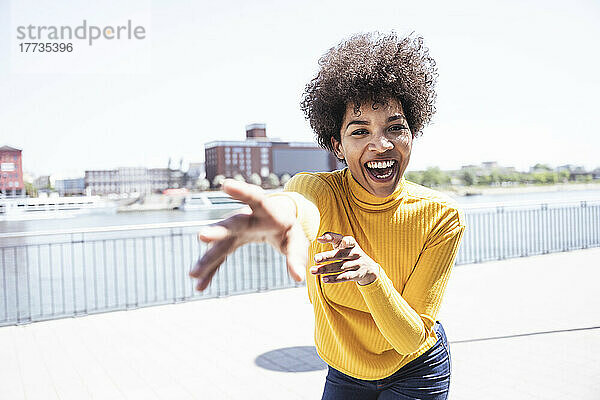 Cheerful woman with Afro hairstyle gesturing enjoying at promenade