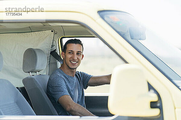 Lächelnder junger Mann  der einen Lieferwagen fährt