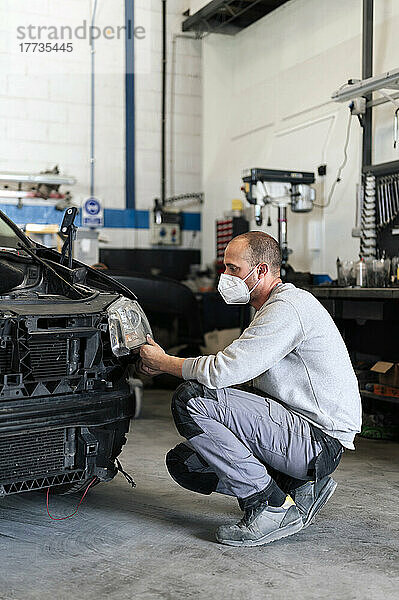 Automechaniker analysiert Scheinwerfer in Werkstatt