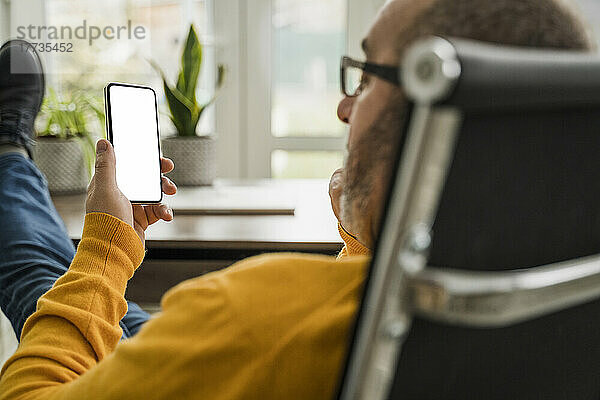 Reifer Geschäftsmann benutzt Mobiltelefon im Büro