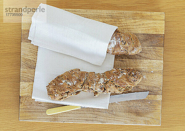 Geschirrtuch und frisches hausgemachtes Pain-Paillasse-Brot auf einem Holzschneidebrett