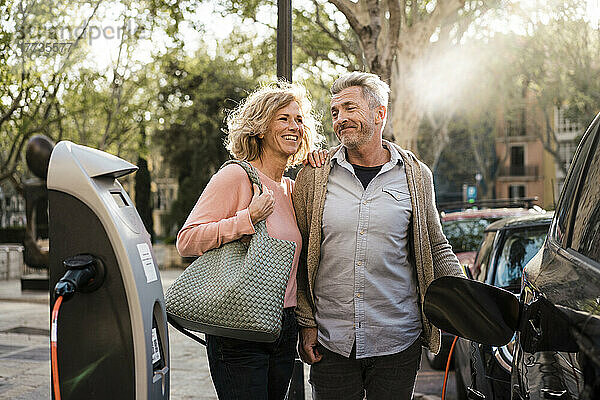 Lächelndes älteres Paar lädt Elektroauto auf