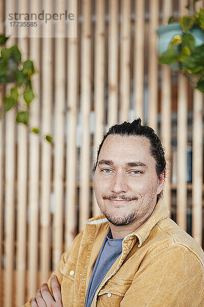 Lächelnder Mann vor einer Holzwand im Café