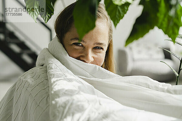 Woman wrapped in white blanket at home